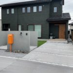オレンジ色のポストがワンポイントの外構